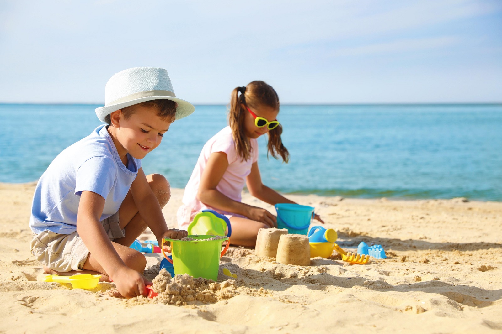 Cute little children playing with plastic toys on sandy beach